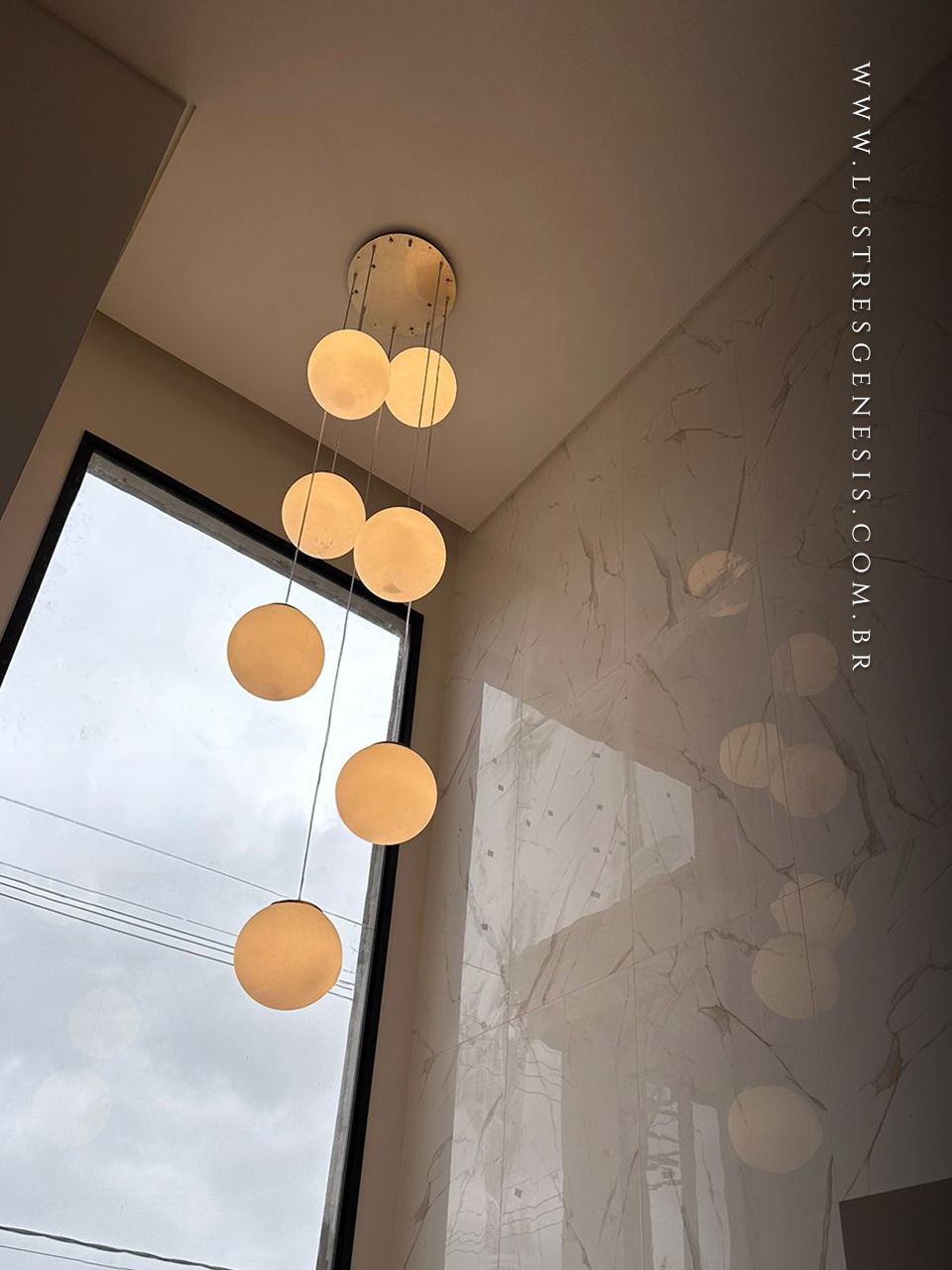 Lustre pendente com 7 globos leitosos foscos, ideal para escadas ou casas com pé direito duplo, da linha Jabuticaba da Loja Gênesis.